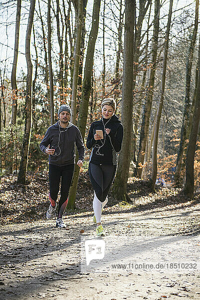 Man and woman jogging on fitness trail in forest