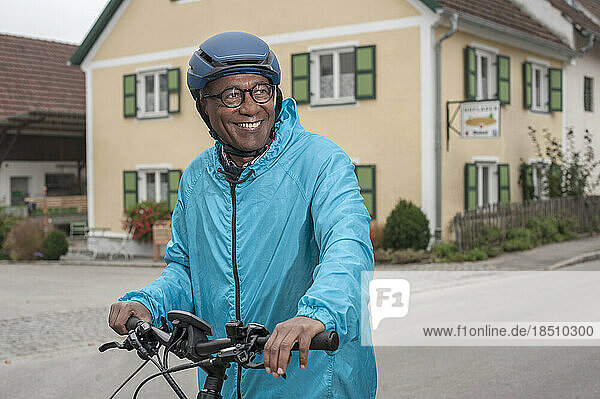 Happy senior man with cycling helmet on his bicycle  Bavaria  Germany