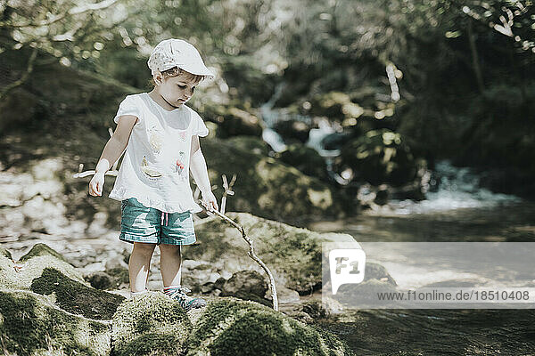 Adorable little girl playing the river in summer  with a cap and shorts.