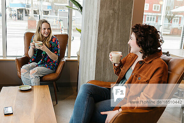 Two young women laughing together in coffee shop