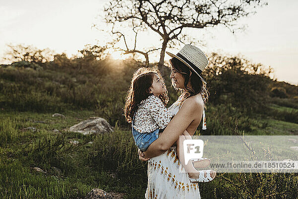 Side view of mother holding daughter while looking at each other