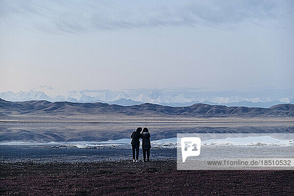 Two female travelers admire the morning landscape  wide angle