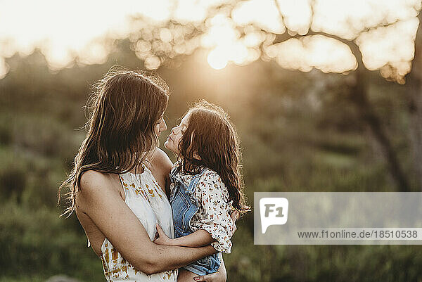 Side view of mother and daughter embracing in sunny field