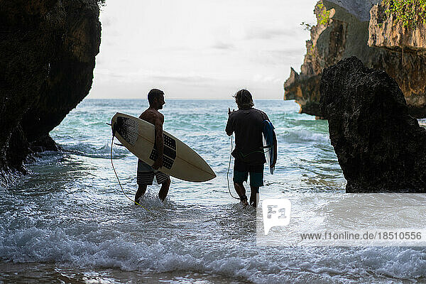 Man with a surfboard goes to the Uluwatu surf spot.