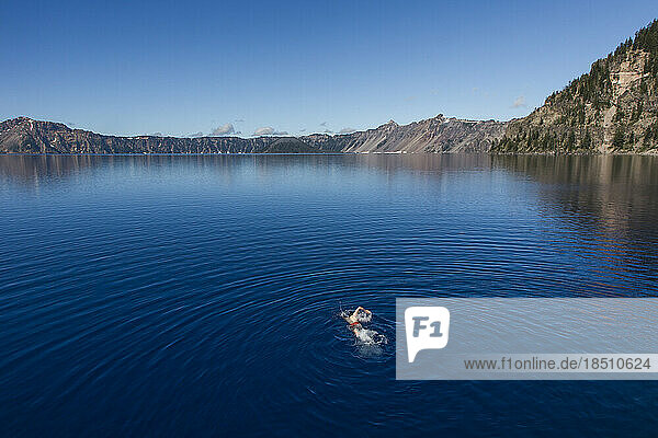 A young man swims in the cold  clear waters of Crater Lake.