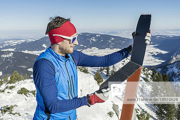 Man holding skis on mountain against sky
