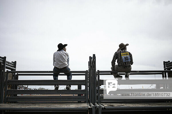 Cowboys sitting on a fence at the Arizona Black Rodeo