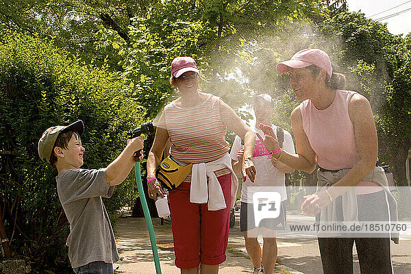 Boy douses a breast cancer walker on a hot day  Cambridge  Massachusetts.