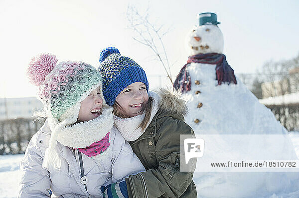 Girls embracing against snowman