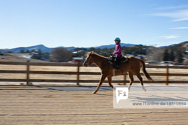 Motion blur of girl riding horse in arena