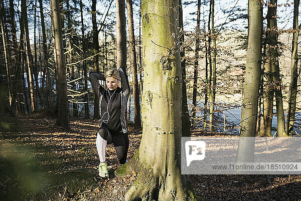 Fit woman stretching on fitness trail in nature