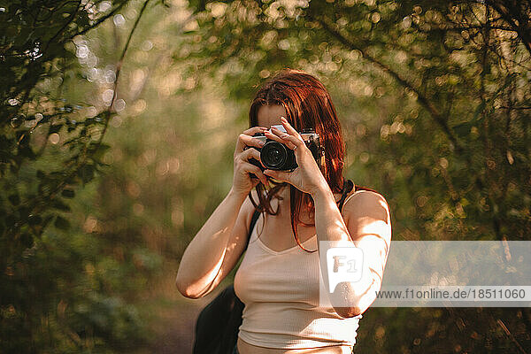 Woman photographing with camera in forest