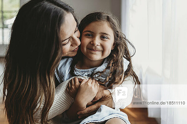 Portrait of 5 year old girl smiling while mother embraces her