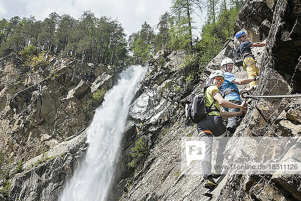 Men climbing on rock via ferrata towards Lehner Waterfall  Otztal  Tyrol  Austria