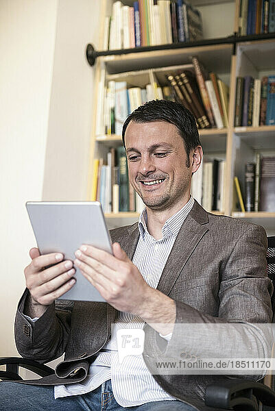 Mature businessman using digital tablet in an office and smiling  Bavaria  Germany