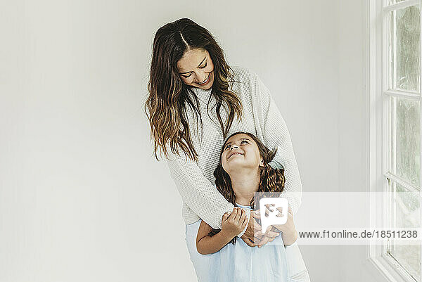 Mother and daughter looking at each other in natural light studio