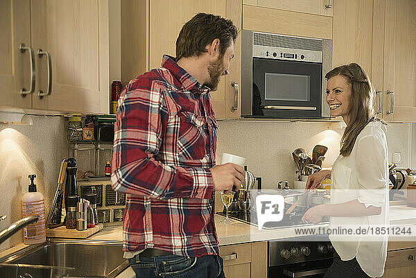 Couple preparing food in the kitchen and smiling  Munich  Bavaria  Germany