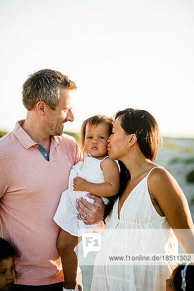 Dad Holding Toddler & Mom Kissing on Coronado Beach in San Diego