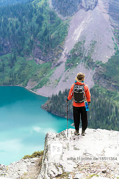 Hiker is standing on a cliff looking at the lake in GlacierNP  Montana