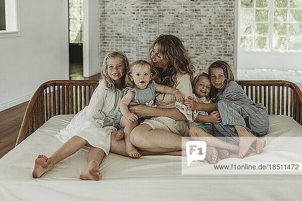 Mother and four daughters sitting on couch in natural light studio