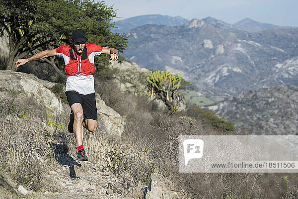 Agile middle aged man jumps over a rock while trail running in El Arenal  Hidalgo  Mexico.
