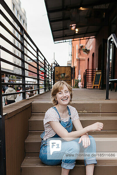 Happy woman sitting on outdoor steps looking at camera