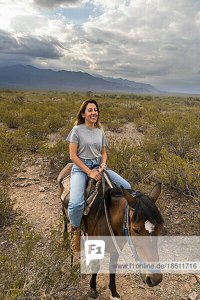 Woman smiling riding a horse in mountains of mendoza argentina