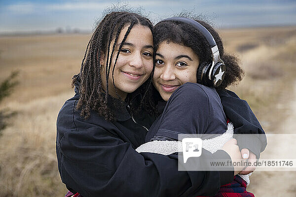 portrait of biracial sisters embracing and smiling