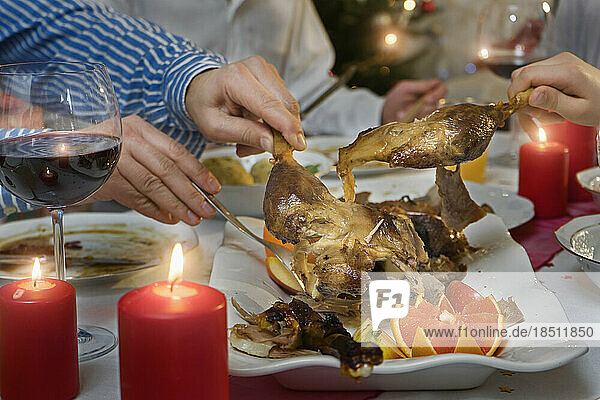 Family carving roasted duck for dinner