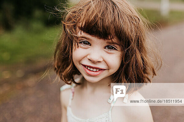 Close up of young smiling girl outside on a cloudy fall day