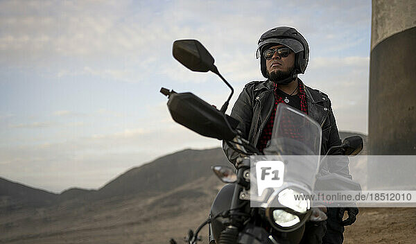 Latin man motorcyclist look at distance.