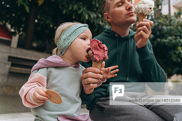 Man and baby eating italian ice cream on the street