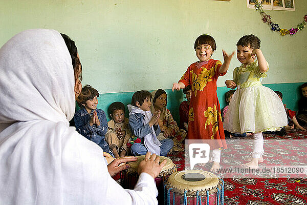 Children dance at a Kabul preschool while their teacher drums a rhythm.