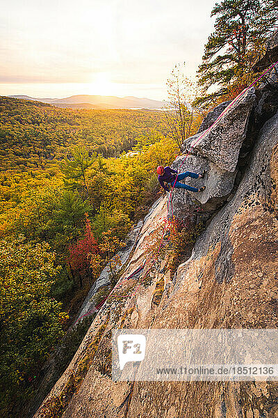 Rock climber rappelling with mountains and foliage in background