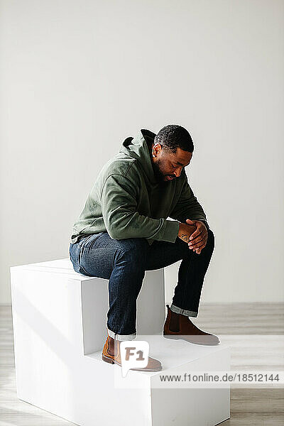 Fashionable Black man sitting and praying indoor