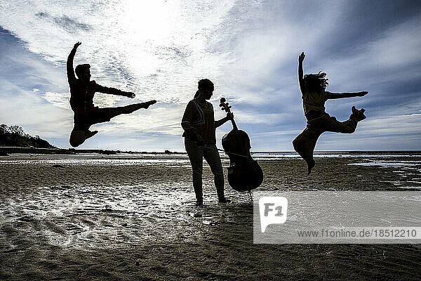 silhouetted dancers and cellist on Cape Cod beach