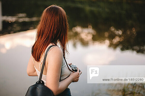 Woman with camera standing by lake