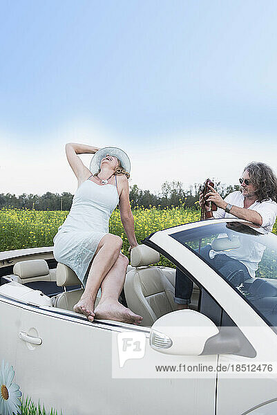 Man photographing happy woman in a car Beetle Cabrio with old school vintage camera  Bavaria  Germany