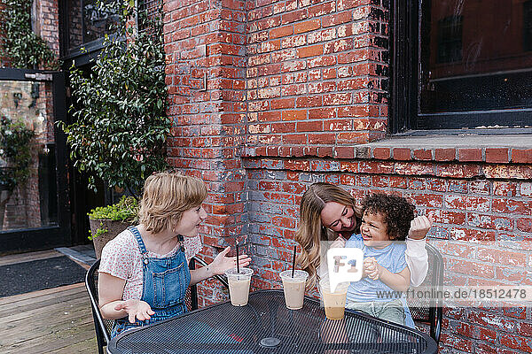 Two adult woman at outdoor cafe with multiracial toddler