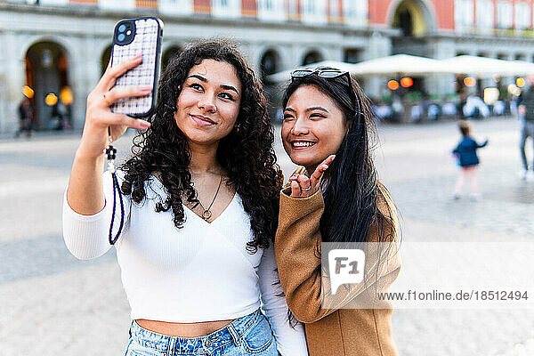 Stock photo of happy friends taking photo with phone