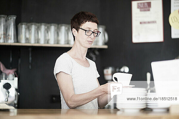 Mature woman drinking coffee in coffee shop  Freiburg im Breisgau  Baden-Württemberg  Germany