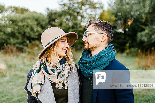 man and a woman in coats are walking through an autumn park on a date