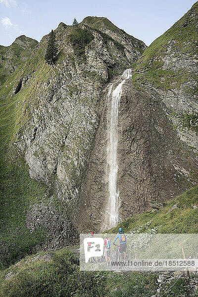 Three mountain biker friends watching waterfall  Zillertal  Tyrol  Austria