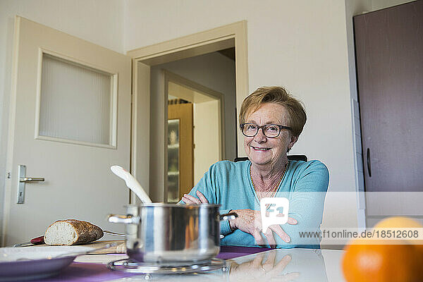 Happy old woman sitting at dining table