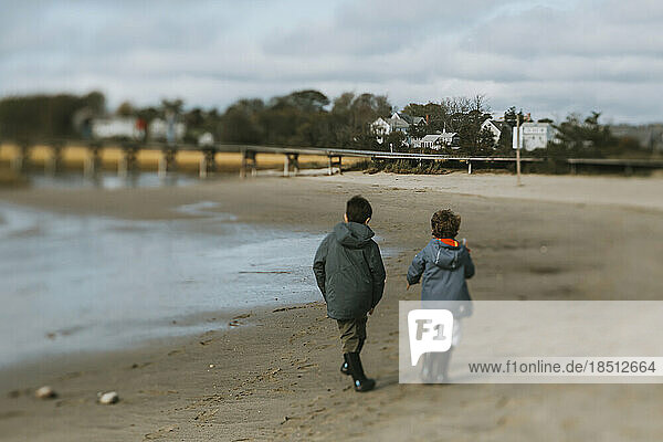 Brothers on beach next to sea inlet  boardwalk and houses in distance