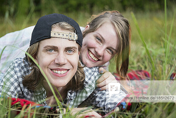 Portrait of a young couple lying in meadow and smiling  Bavaria  Germany