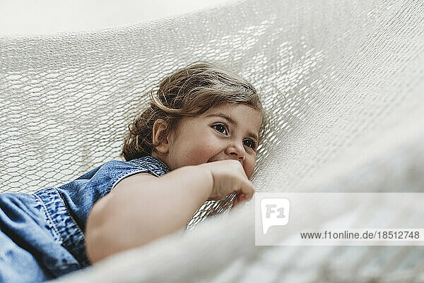 Young preschool aged girl resting in hammock looking away