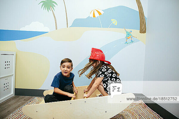 Girl and boy rock on a seesaw inside an educational facility