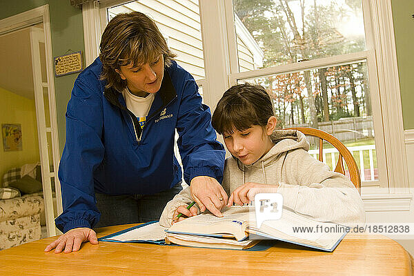 A mother helps her ten-year-old daughter with her homework.