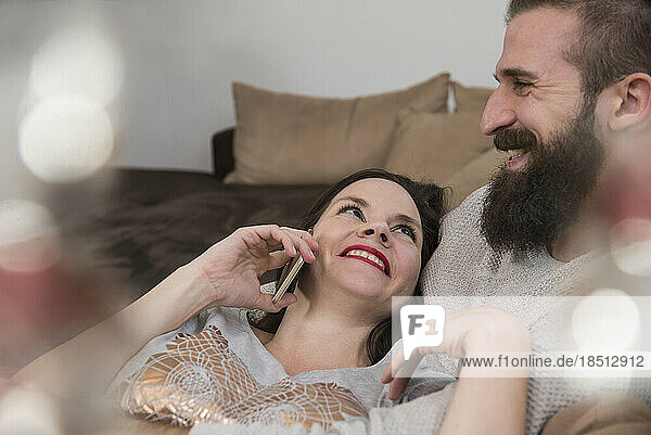 Woman talking on cell phone with her husband on sofa